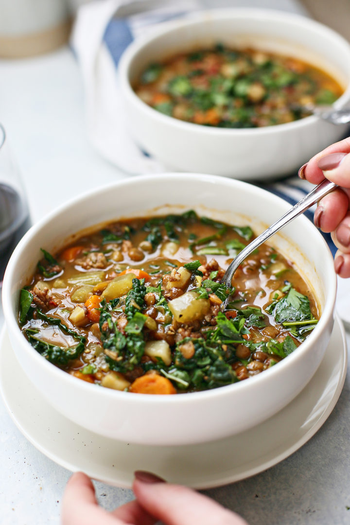 woman eating a bowl of this recipe for instant pot lentil soup