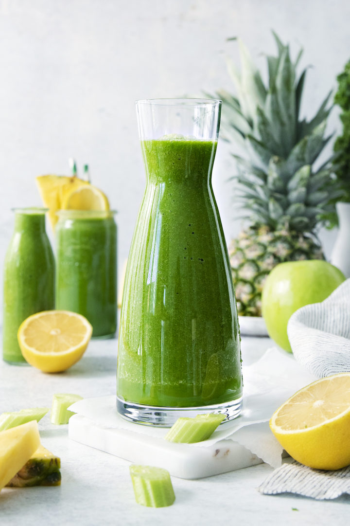 table set with glasses of kale pineapple smoothie and fresh fruit