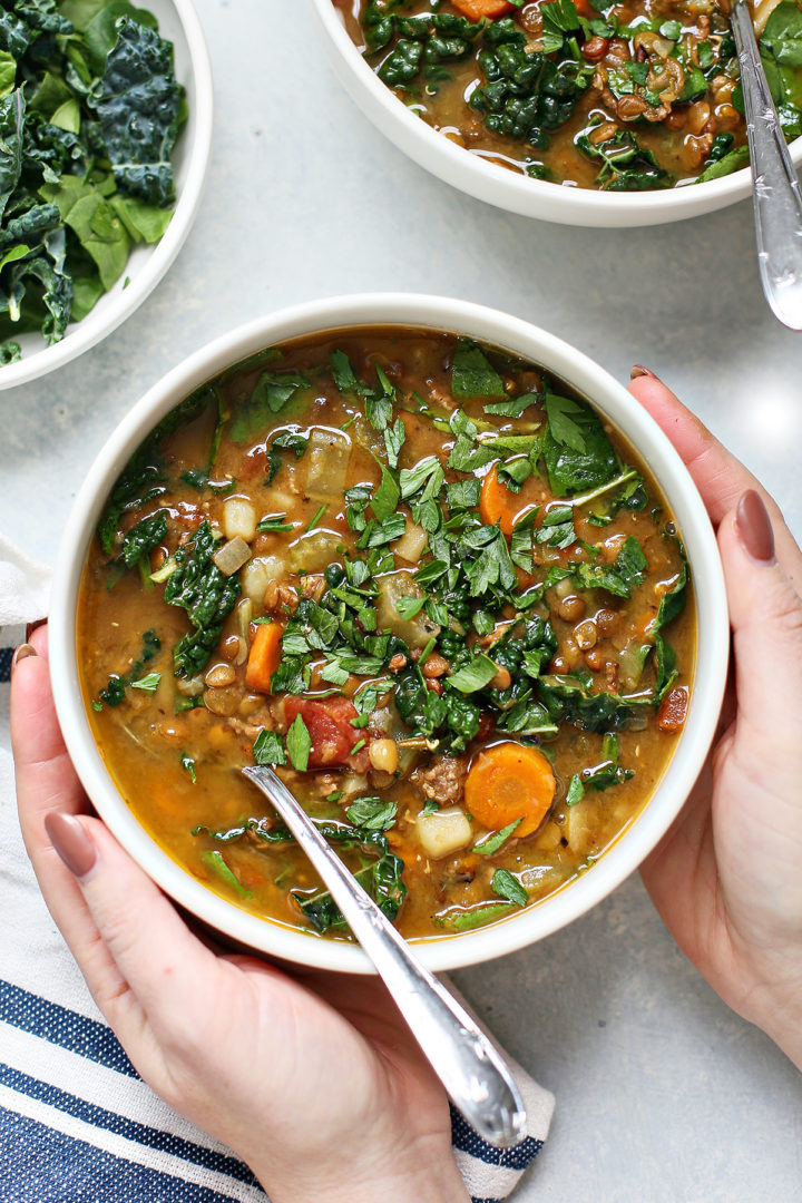 woman holding a bowl of instant pot lentil soup