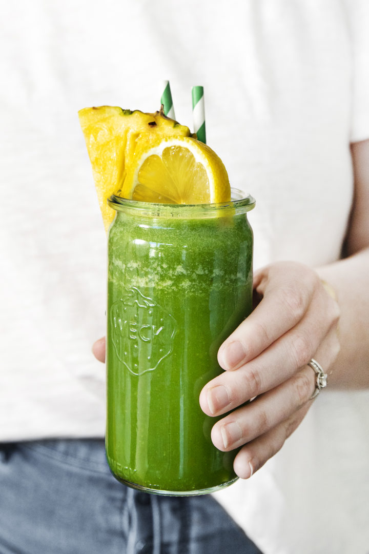 woman holding a glass of kale green apple smoothie