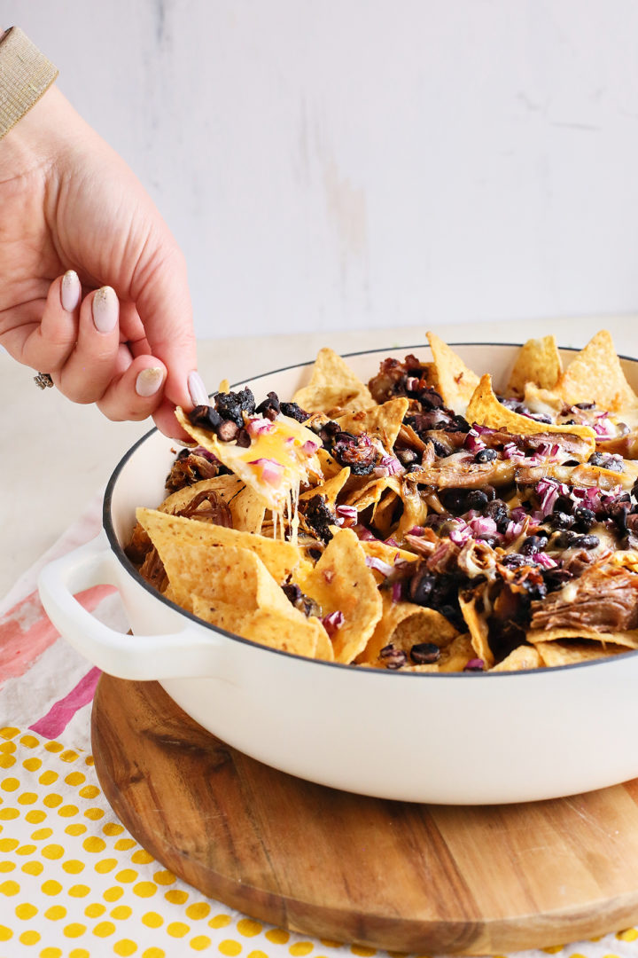 woman eating shredded pork nachos 
