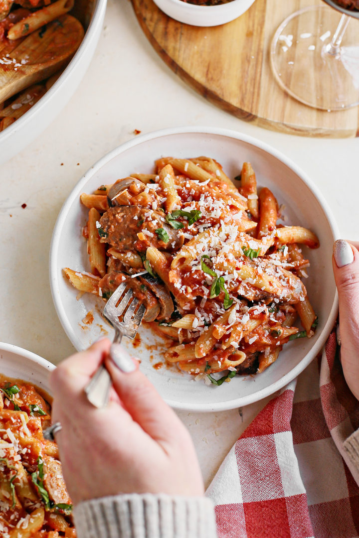 woman eating a bowl of penne with vodka sauce and sausage