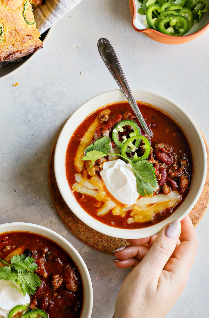 woman holding a bowl of kidney beef chili with ground beef