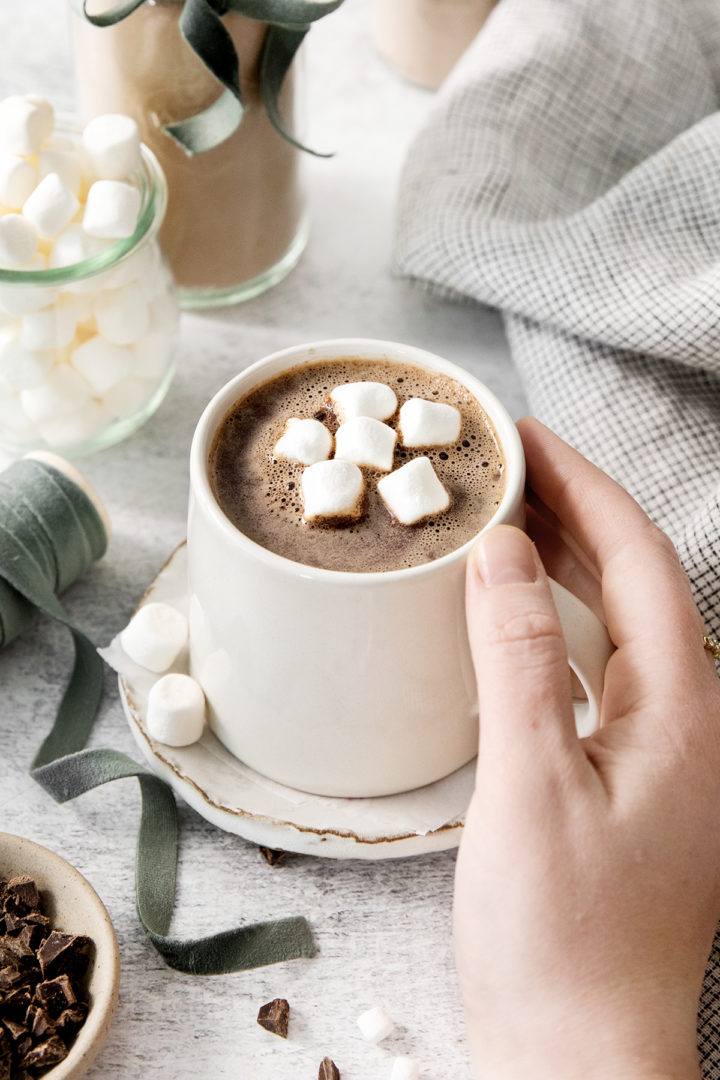 woman picking up a mug of hot cocoa prepared using homemade hot cocoa mix