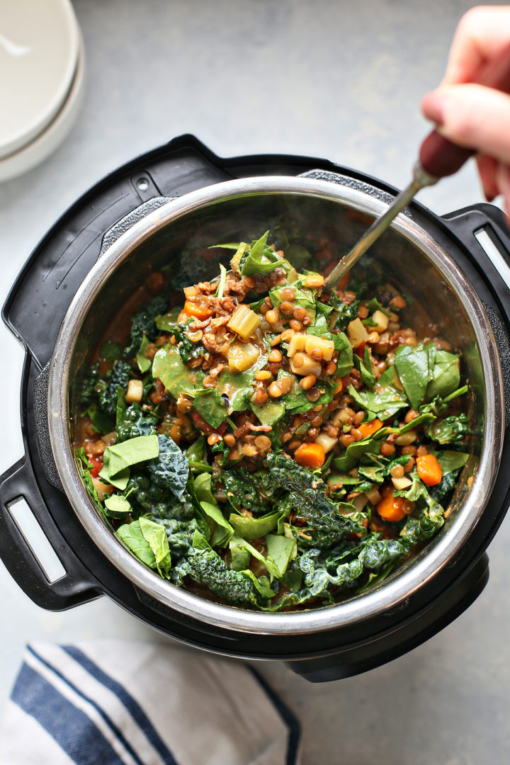 stirring kale and spinach into pressure cooker lentil soup