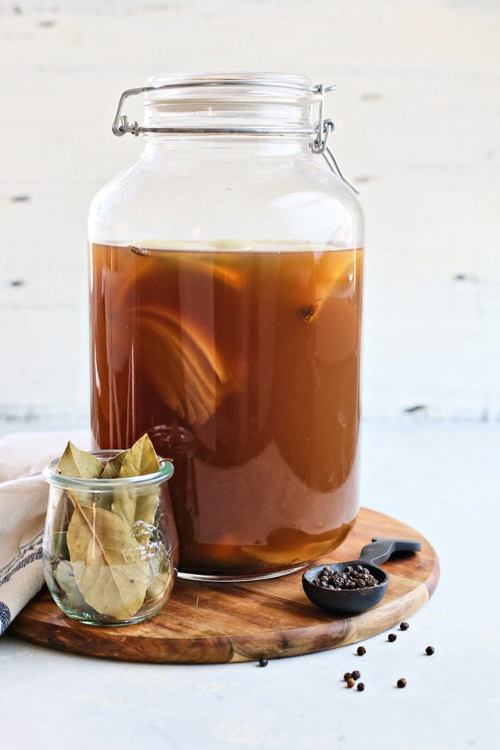 a brine in a jar sitting on a wooden cutting board used for preparing the traeger pork shoulder recipe