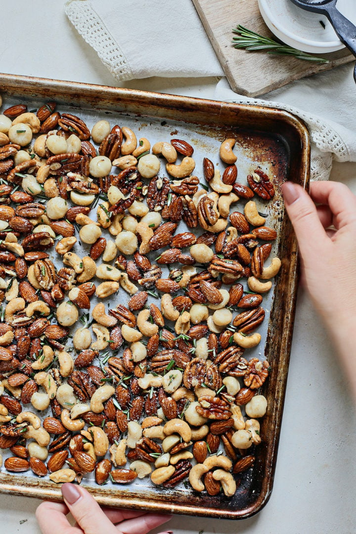 woman holding a baking sheet of mixed bar nuts