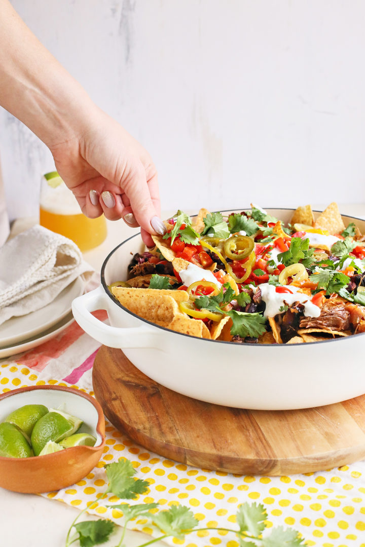 woman serving pulled pork nachos