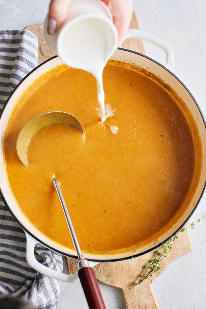 woman pouring cream into butternut squash and apple soup	