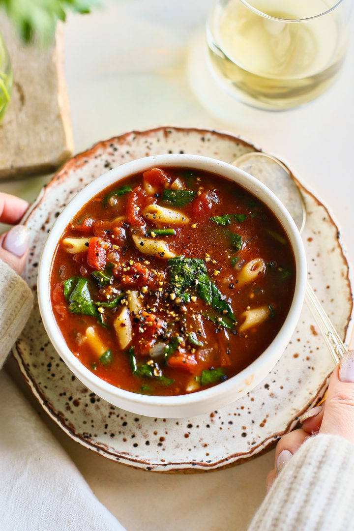 woman holding a bowl of tomato florentine soup