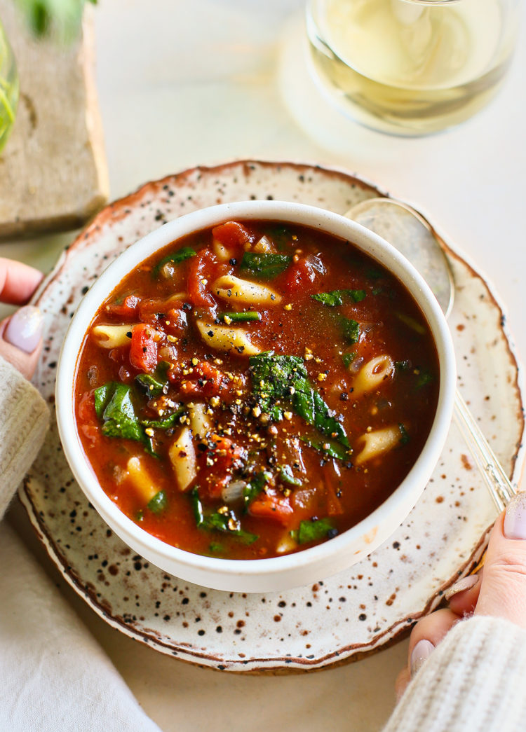 woman holding a bowl of tomato florentine soup