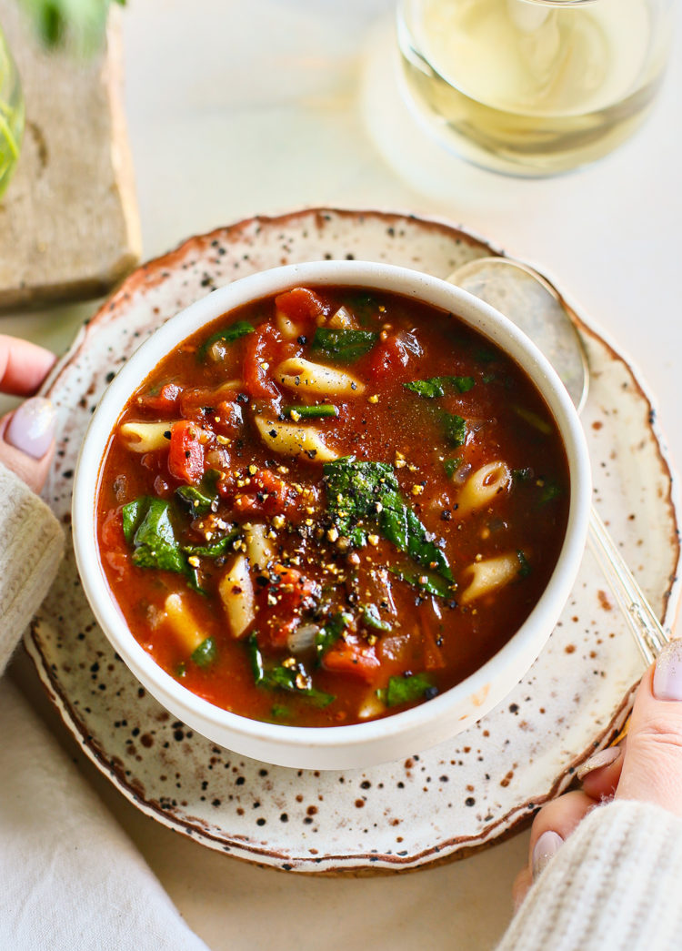 woman holding a bowl of tomato florentine soup