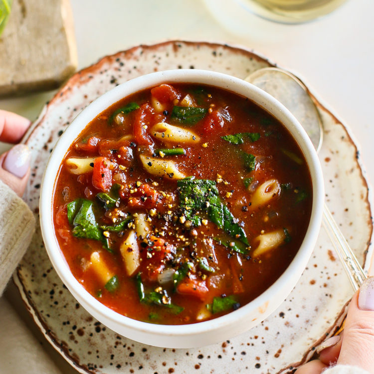 woman holding a bowl of tomato florentine soup