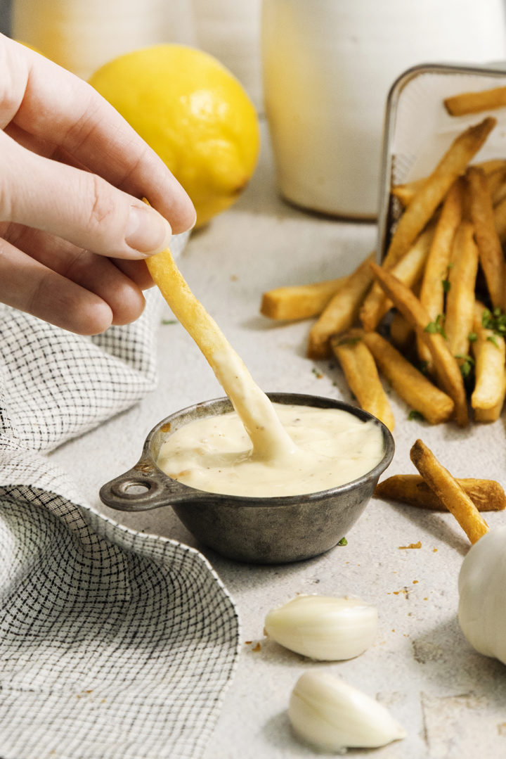 woman dipping fries in homemade roasted garlic aioli