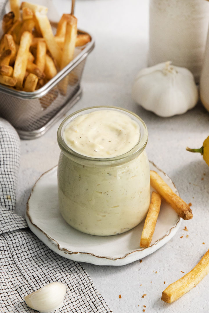 homemade garlic aioli in a jar with a basket of french fries for dipping