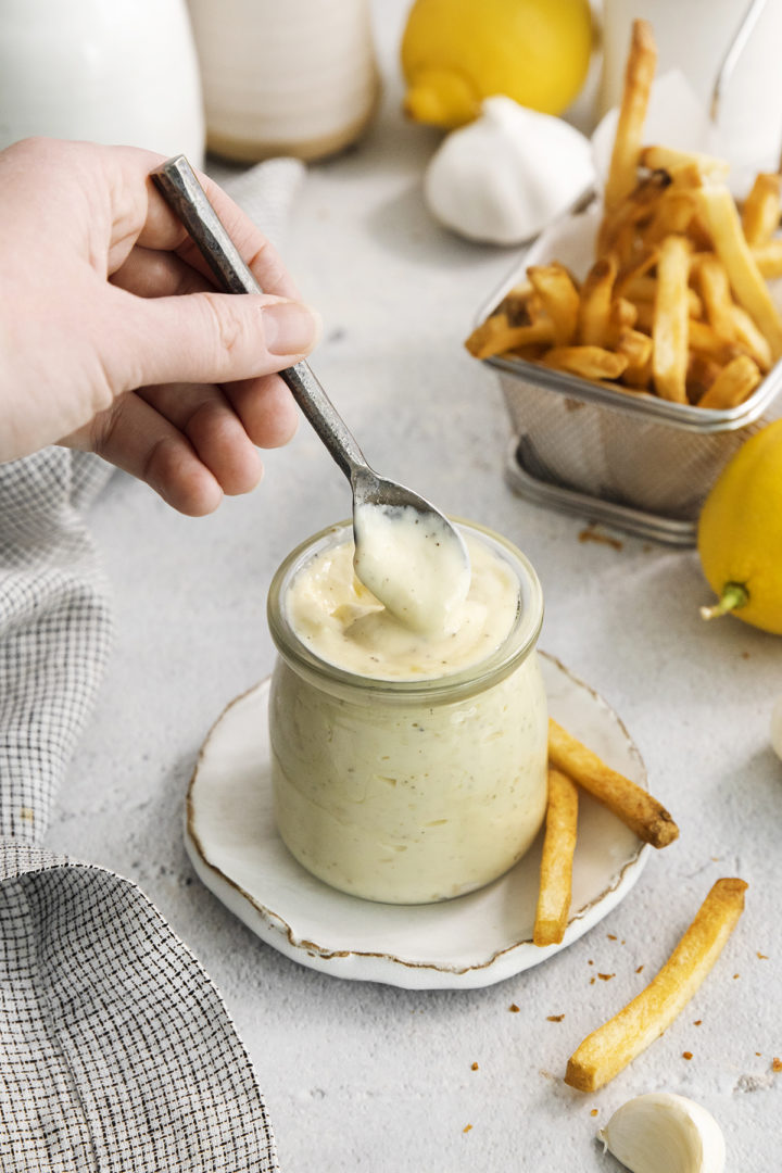 woman stirring a jar of garlic aioli sauce