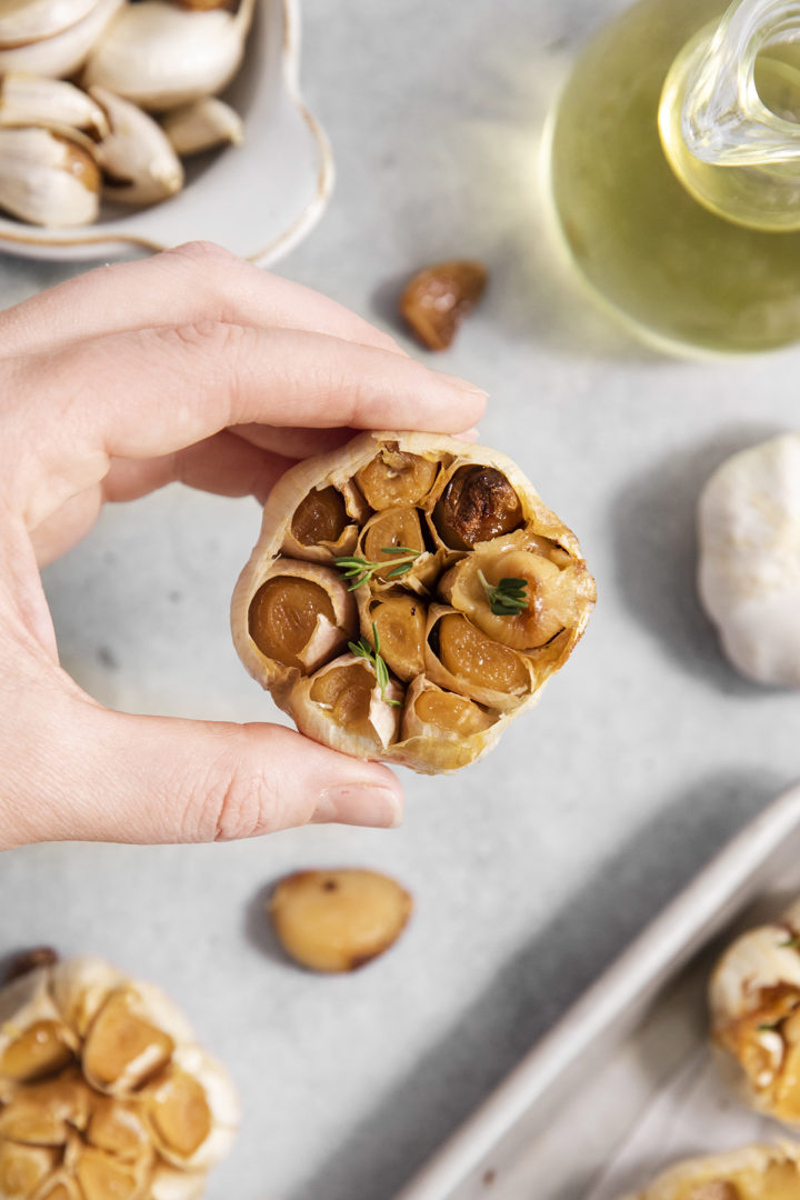 woman holding a head of roasted garlic