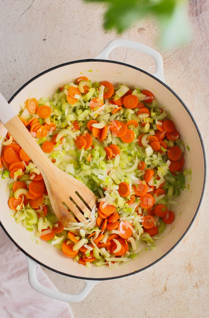 carrot, leek, and celery for old fashioned chicken noodle soup being sautéed in a cast iron pot