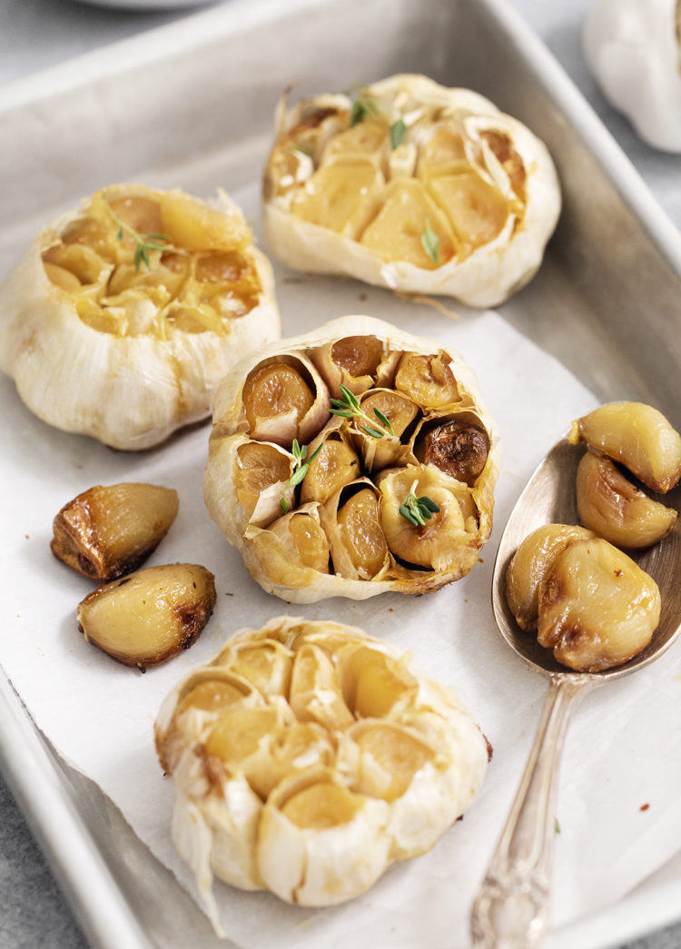 whole heads of roasted garlic on a baking sheet