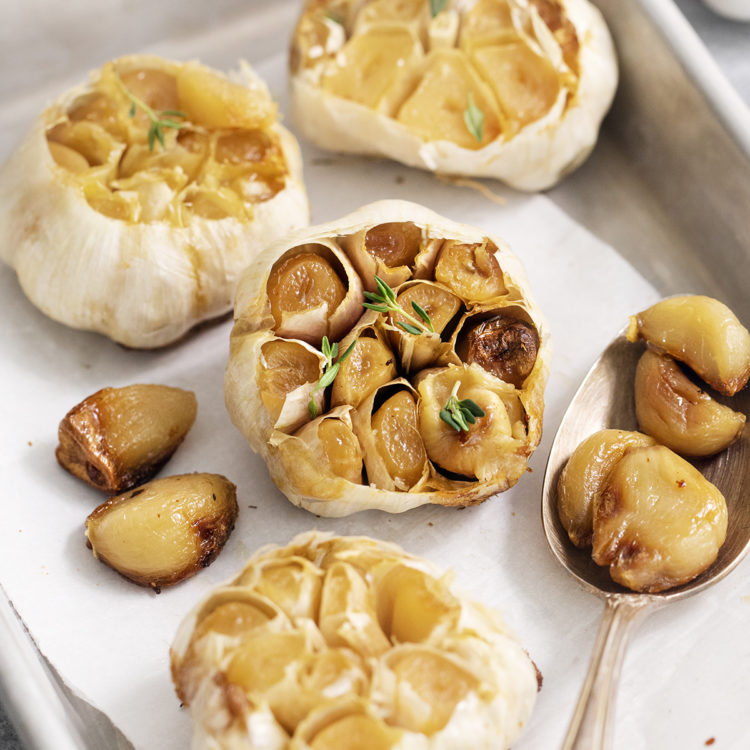 whole heads of roasted garlic on a baking sheet