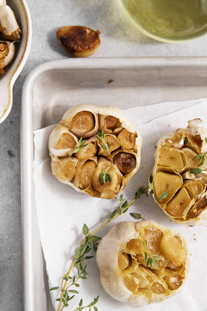 3 roasted garlic heads with sprigs of fresh thyme