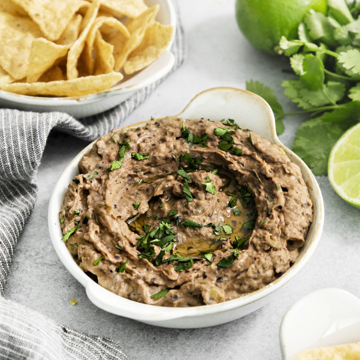 black bean hummus in a white dish next to tortilla chips