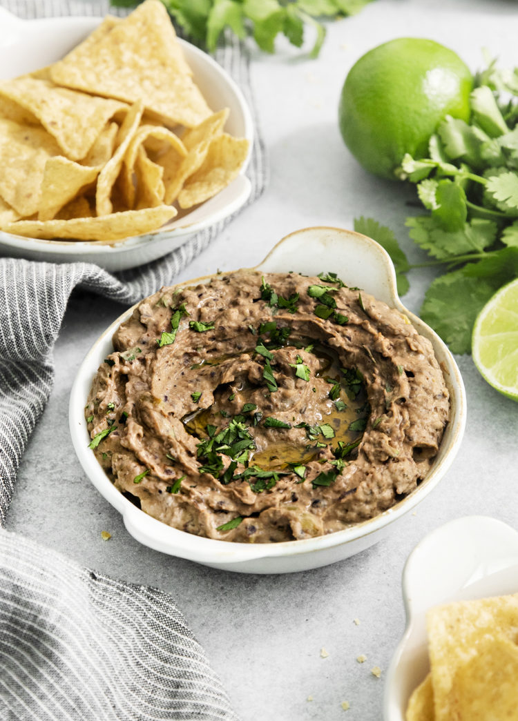 black bean hummus in a white dish next to tortilla chips