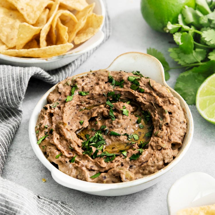 black bean hummus in a white dish next to tortilla chips