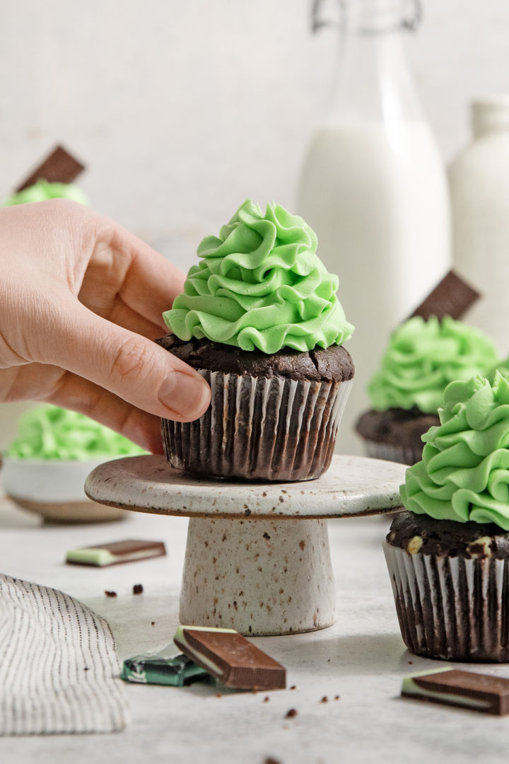 woman picking up a mint chocolate cupcake