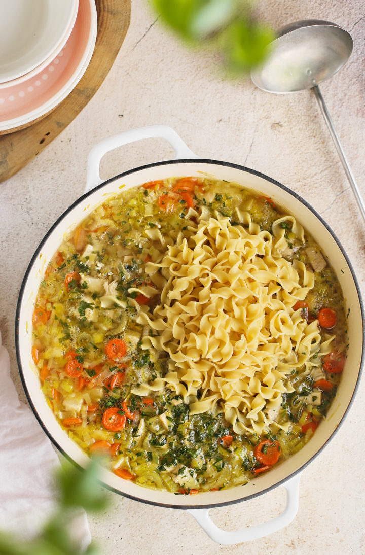 a cast iron pot with chicken egg noodle soup in it