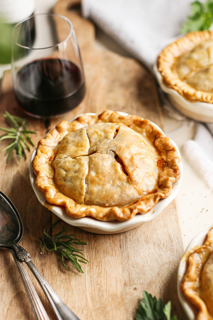 a mini chicken pot pie on a cutting board with a glass of wine