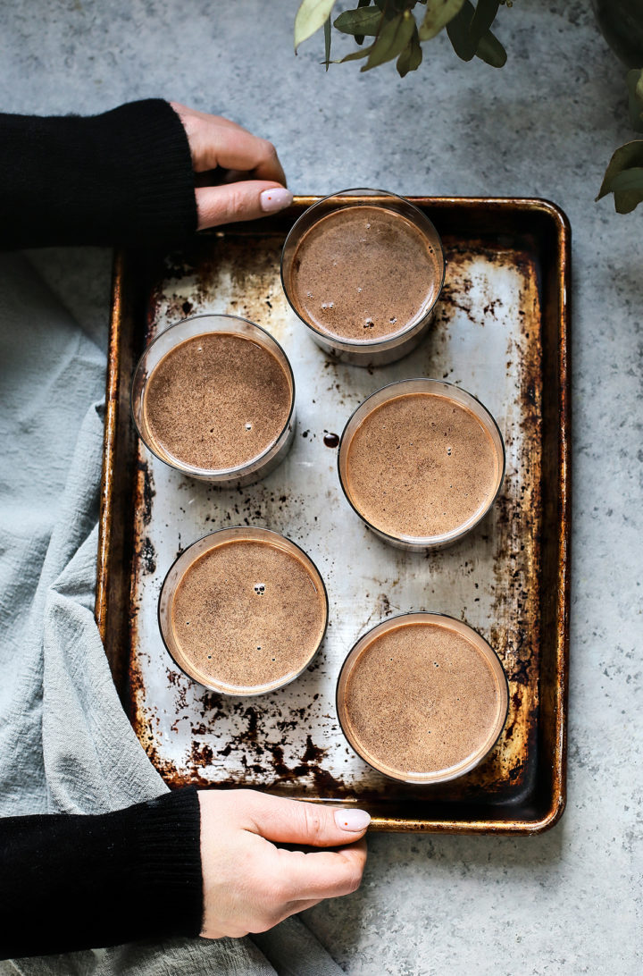 woman holding a tray of easy chocolate pudding in glasses