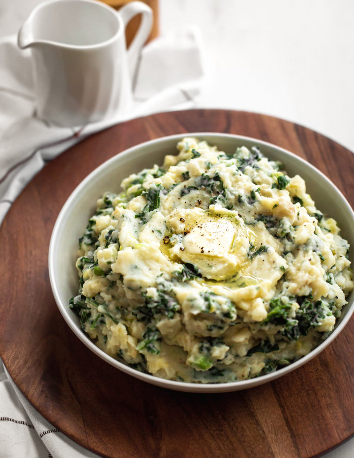 white bowl of irish mashed potatoes (colcannon recipe) on a wooden tray