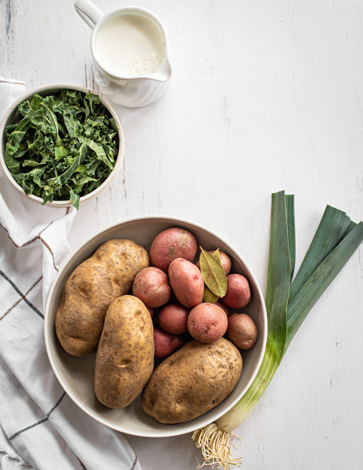 ingredients needed to make colcannon potatoes (irish mashed potatoes) on a white farmhouse table