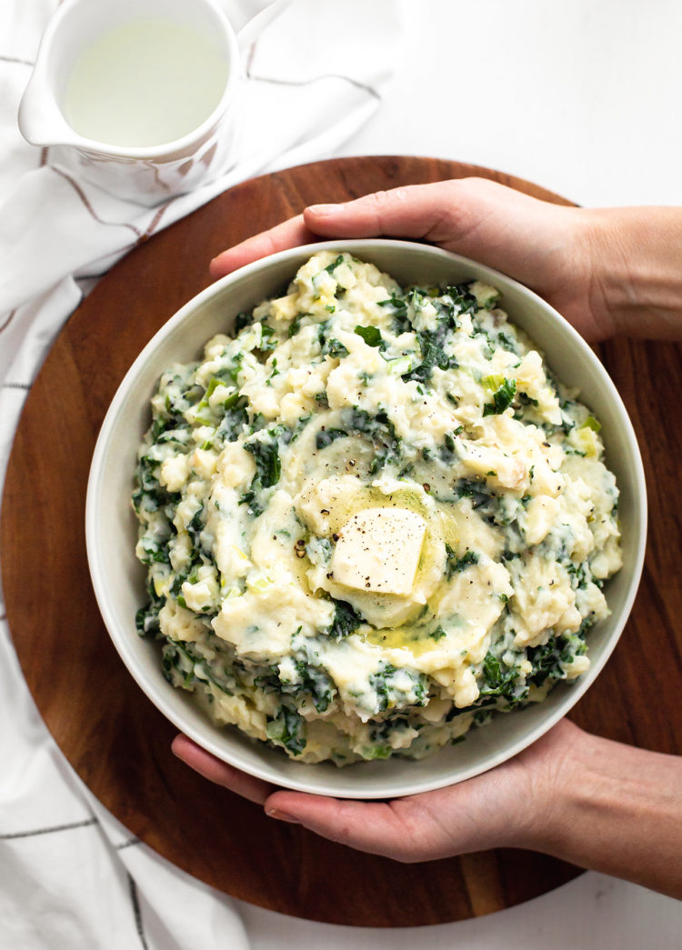 woman holding a bowl of Easy Colcannon Recipe (Irish Mashed Potatoes with Leeks and Kale)