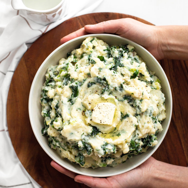 woman holding a bowl of Easy Colcannon Recipe (Irish Mashed Potatoes with Leeks and Kale)