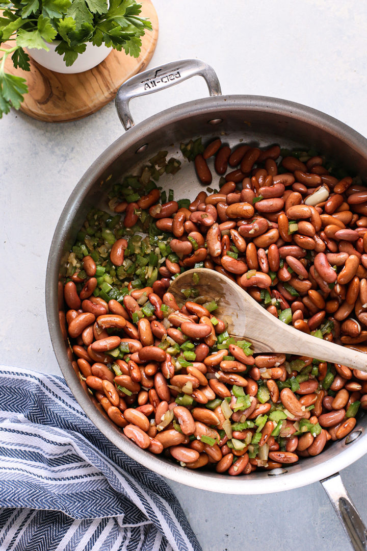 adding beans to a stainless steel pan for a red beans and rice recipe
