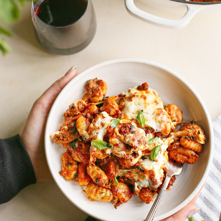 woman holding a plate of gnocchi bake