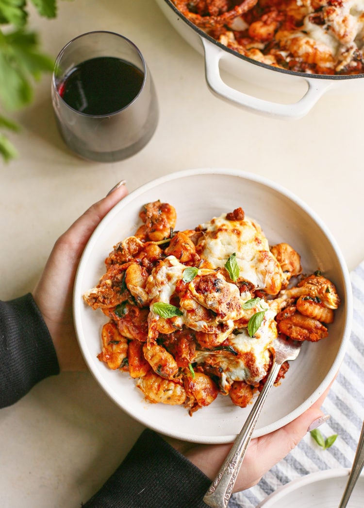 woman holding a plate of gnocchi bake