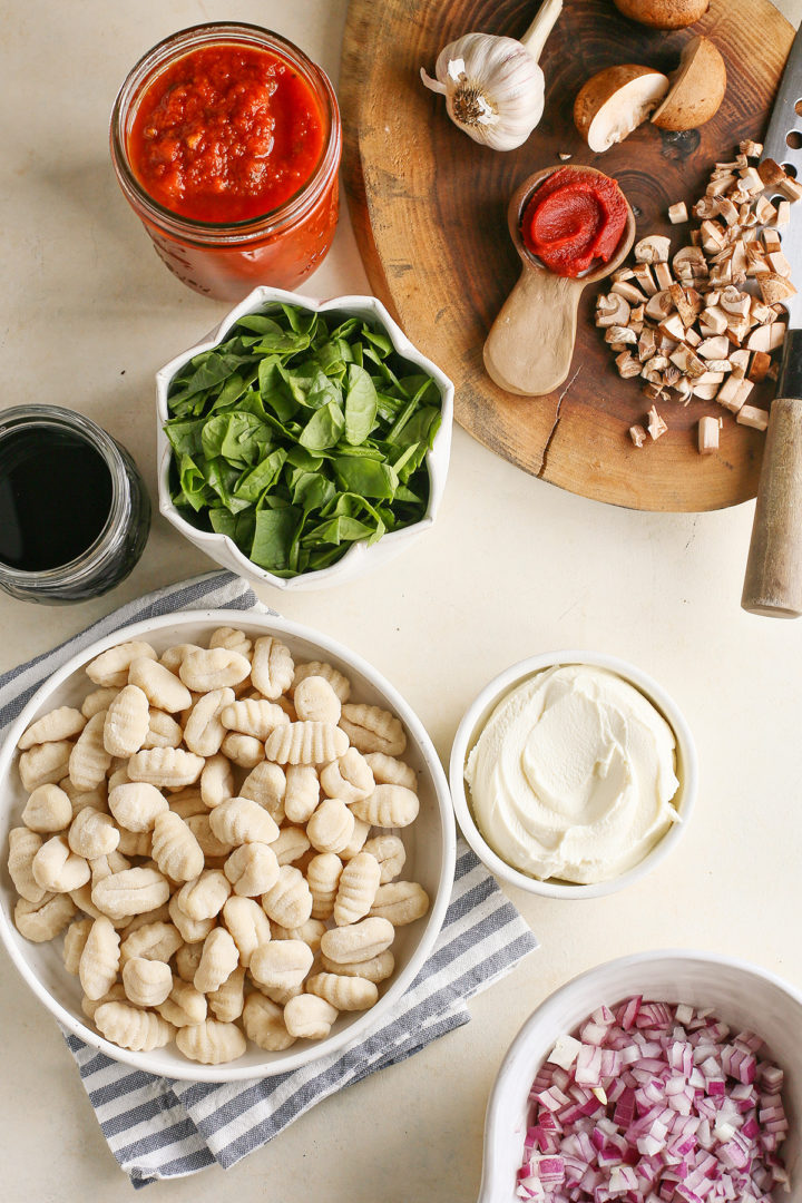 ingredients needed to make Cheesy Italian Sausage Gnocchi Bake arranged on a cutting board