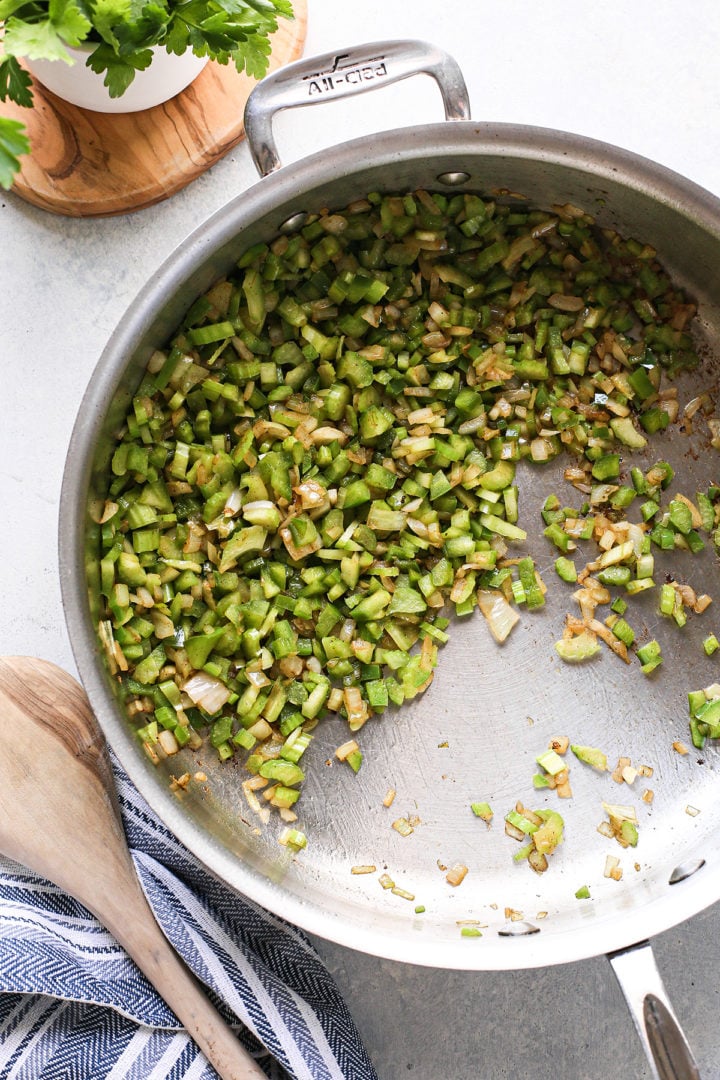 green bell pepper, celery, and onion cooking in a stainless steel pain for an easy red beans and rice recipe 
