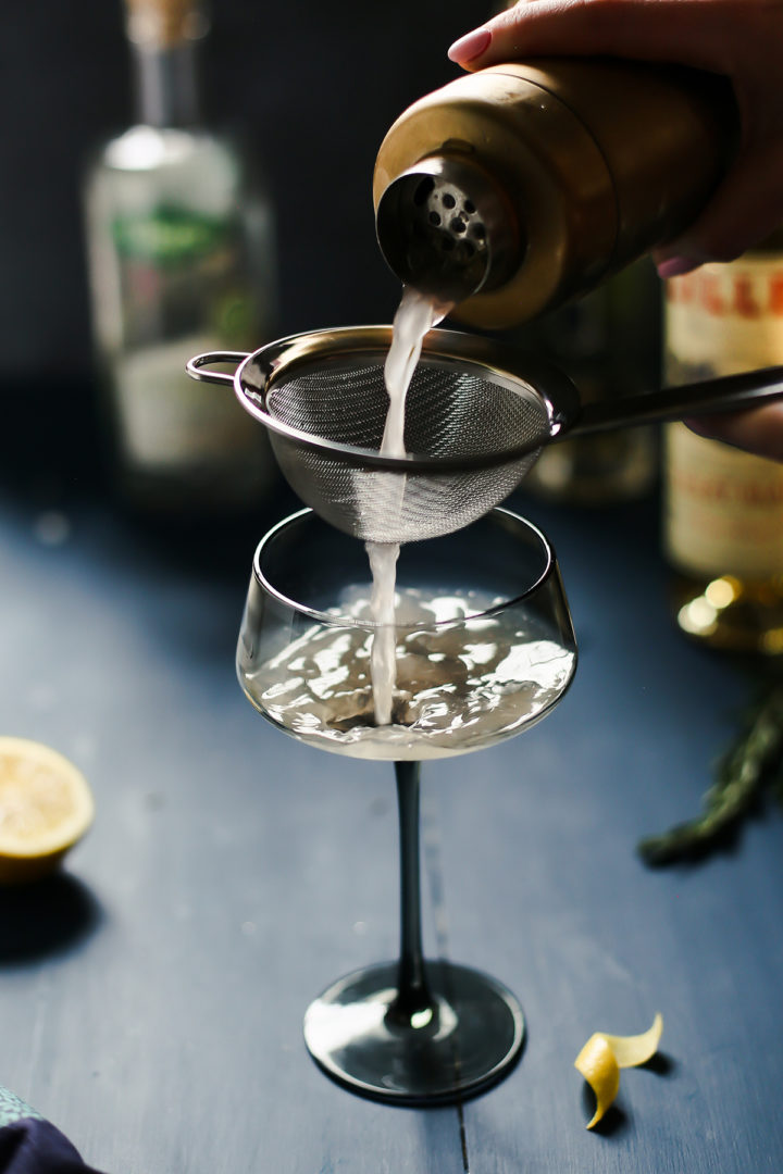 woman straining a french blonde cocktail into a glass