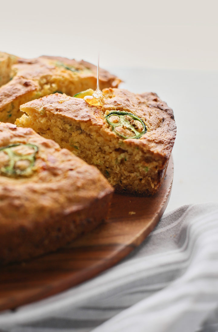 honey being drizzled on a slice of cornbread with jalapeños
