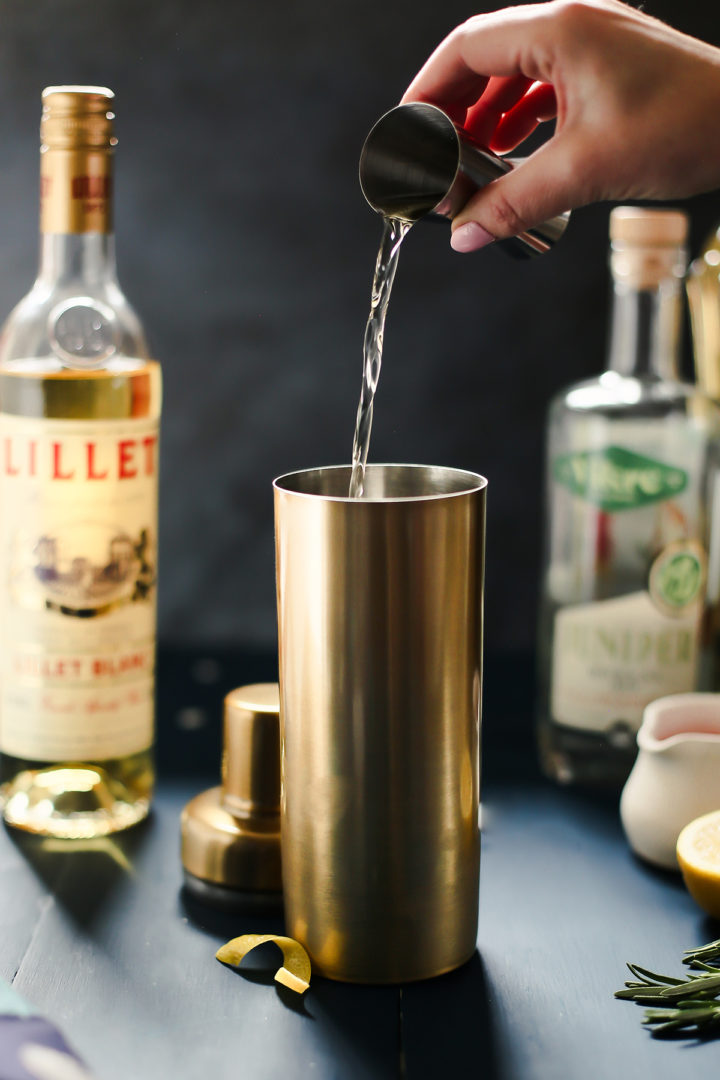 woman pouring lillet blanc into a cocktail shaker