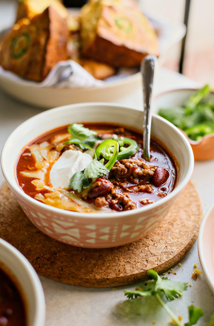 a bowl of chili next to a basket of the best jalapeño cornbread recipe

