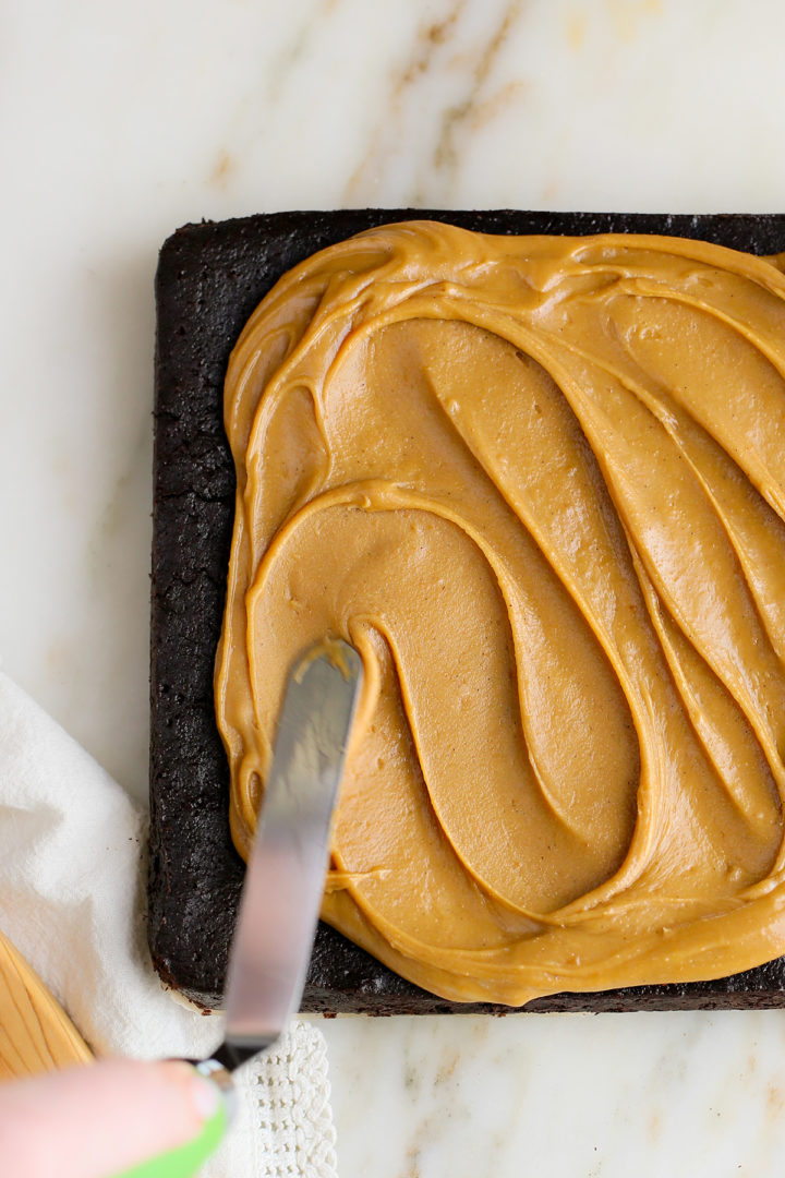 woman spreading caramel frosting on guinness brownies for st patrick's day