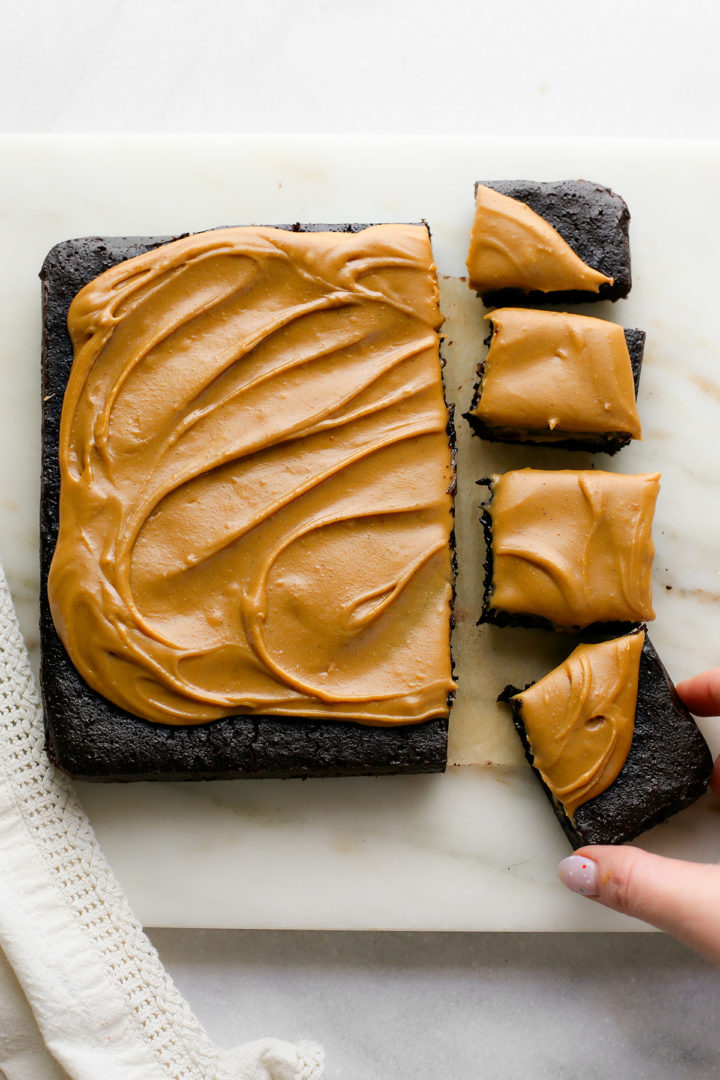 woman picking up a guinness brownie with caramel frosting