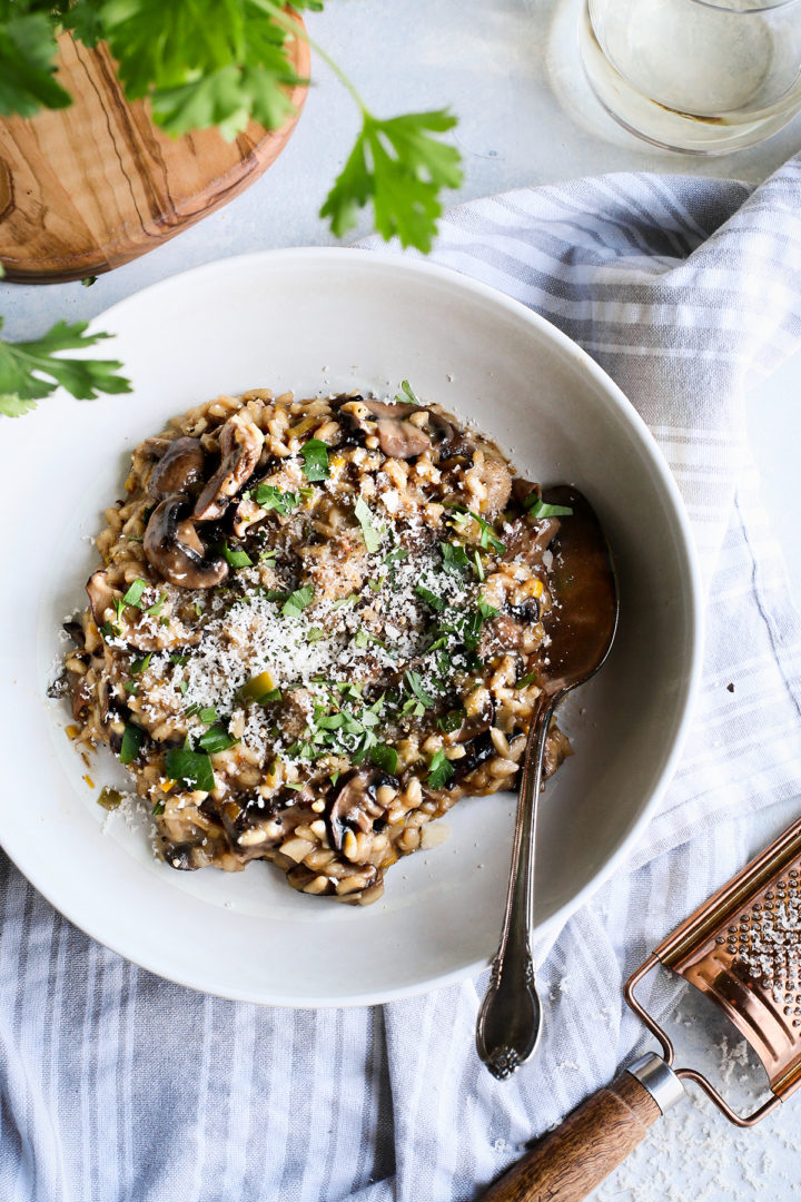 creamy mushroom risotto in a white bowl with a spoon