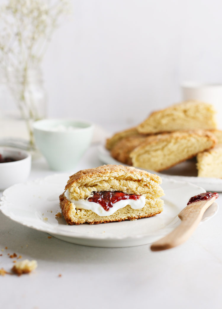 basic scone on a plate served with raspberry jam and a knife next to a plate of fresh homemade scones