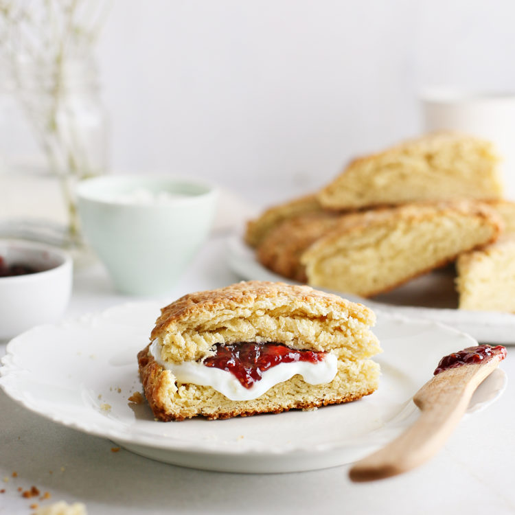 basic scone on a plate served with raspberry jam and a knife next to a plate of fresh homemade scones